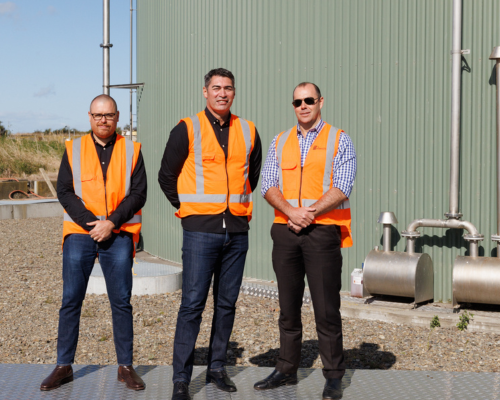 Powerco people in high-vis standing in front of a biogas digester